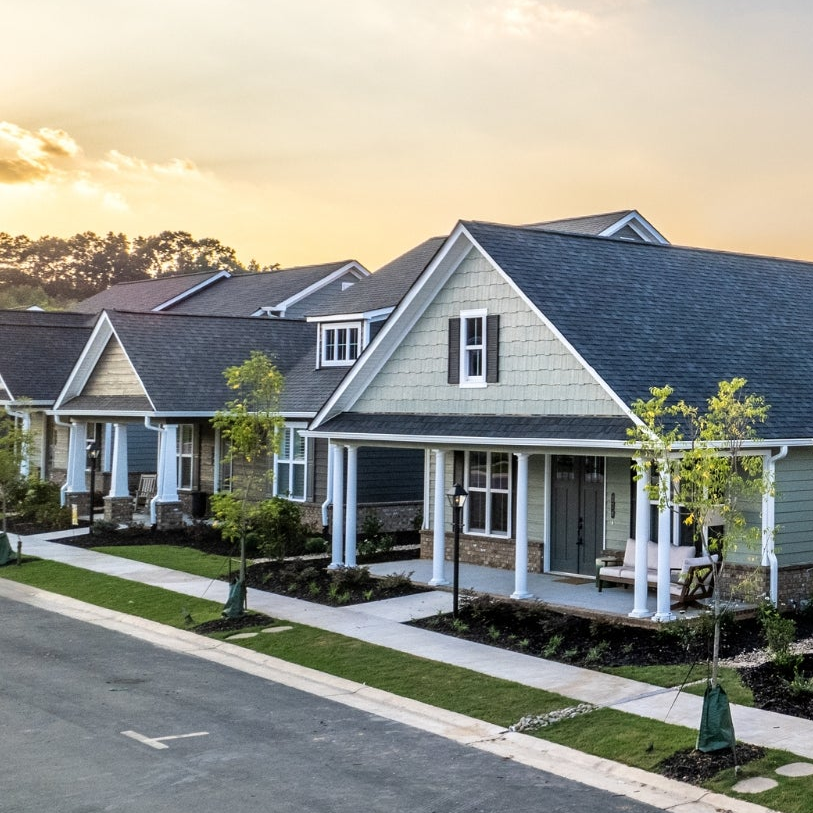Row of houses with well-maintained lawns and driveways during sunset.